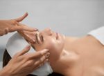 Side view of smiling young woman on procedure for improvements face skin in beautician. Concept of procedure for rejuvenation skin or improvements in professional salon.